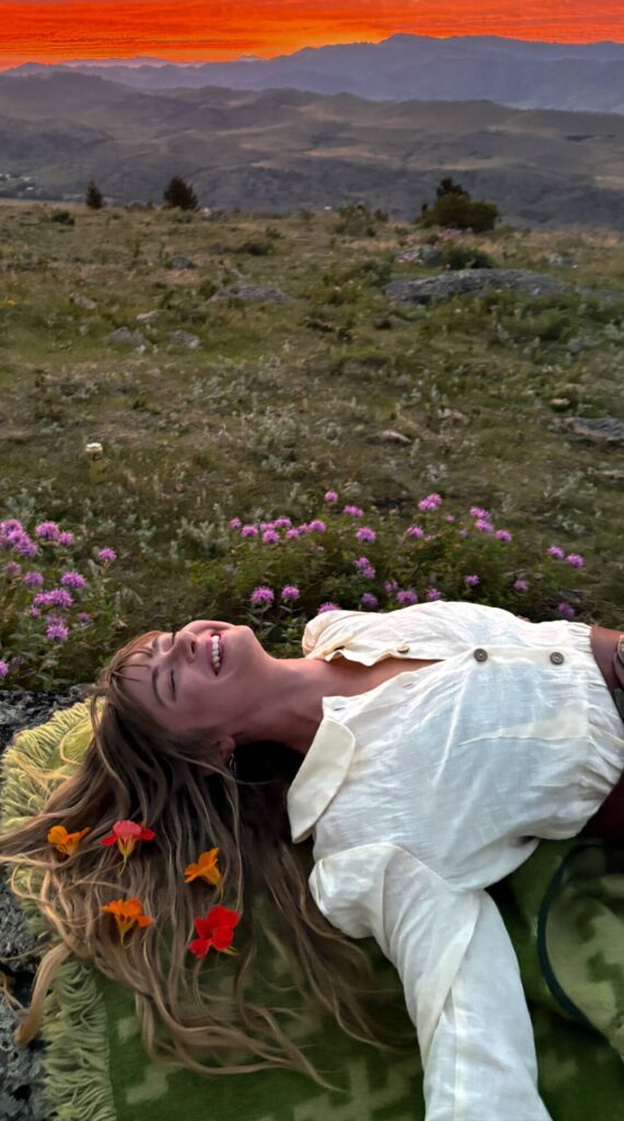 Abby with flowers in hair laying in a meadow at sunset
